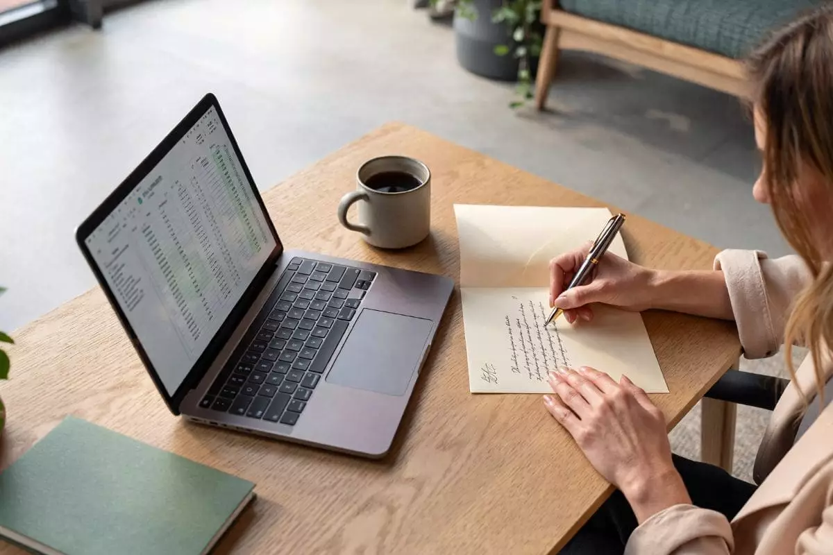 Personne utilisant un modèle de lettre pour rédiger un courrier personnalisé sur un bureau